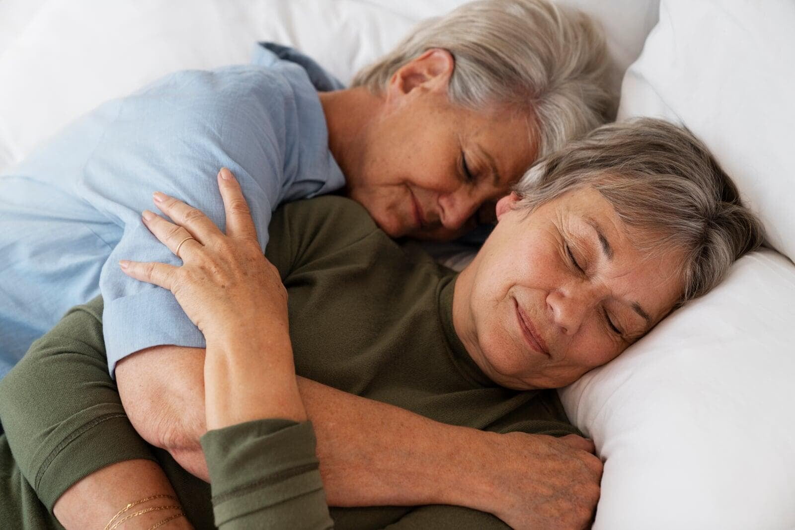 Female couple hugging in bed
