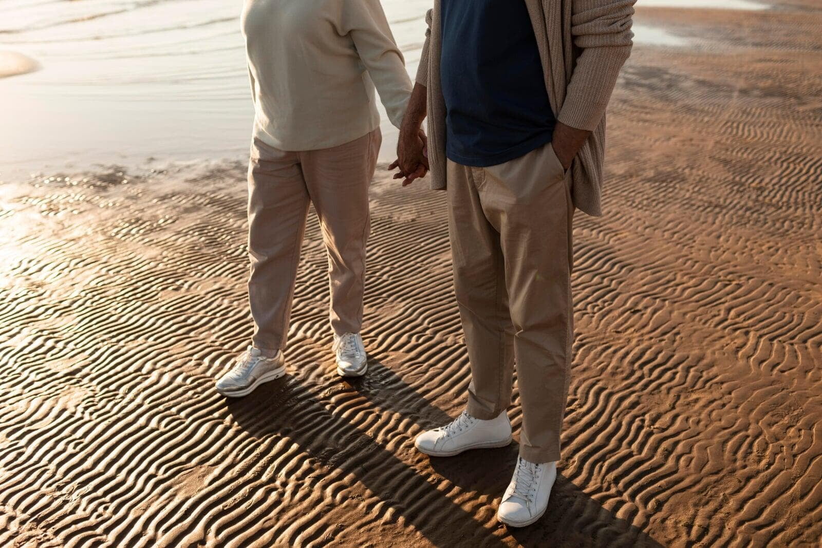 Close-up of partners holding hands by the seaside